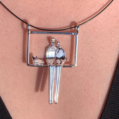 Silver pendant of couple seated in an embrace next to cat